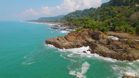 Ocean waves crashing against rock formation along Costa Rica coastline Видео 344914330