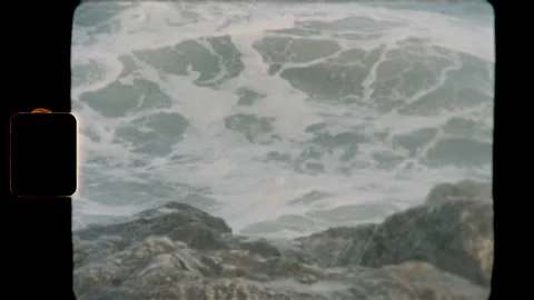 Ocean waves crashing against rocks on vintage Super 8 film Stock Footage 345489668