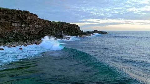 Ocean waves crashing against rugged rocky coastline at golden sunrise aerial Stock Footage 343696479