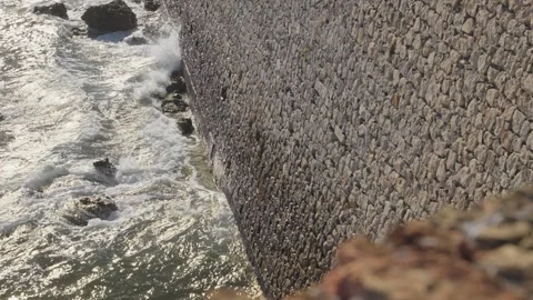 Ocean waves crashing against stone seawall 動画素材 339098137