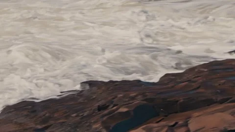 Ocean waves crashing on dark rocks, creating white foam and flowing water Stock Footage 341323268