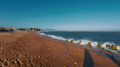 Ocean Waves Crashing on Mossy Blocks along Sandy Beach Shoreline Stock Footage 336921857