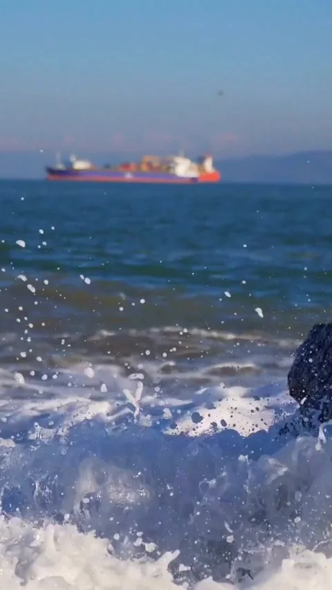 Ocean waves crashing on rocks with ship in background Stock-Footage 334169296