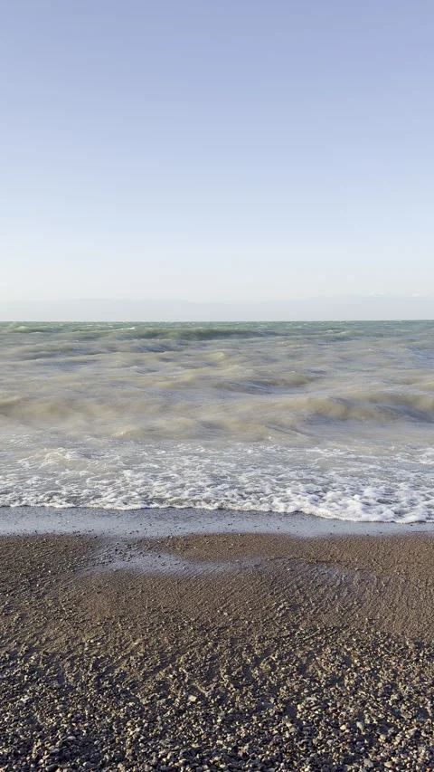 Ocean waves crashing on rocky beach under clear blue sky 24s Stock Footage 340764642
