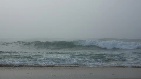 Ocean waves crashing on sandy beach on a very foggy day in winter Stock Footage 95153044