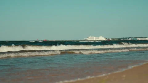 Ocean waves crashing on sandy beach with cruise ship in background Stock Footage 312207825