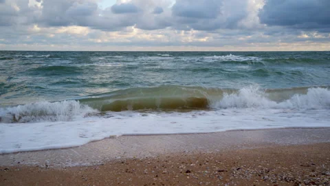 Ocean Waves Crashing on Sandy Beach Under Cloudy Sky Stock Footage 313609624