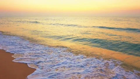 Ocean waves crashing on sandy beach during golden sunset Stock Footage 332729115