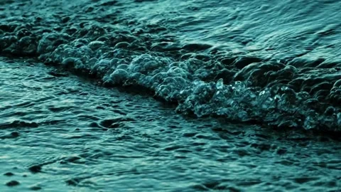 Ocean waves crashing on a sandy beach at sunset Vídeos de archivo 339133872