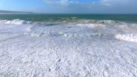 Ocean waves crashing onto a sandy beach with white foam Stock-Footage 341328198