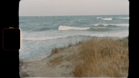 Ocean waves crashing on a sandy beach with dunes on Super 8 film Stock Footage 345489603