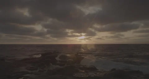 Ocean waves crashing into a stone cliff at sunset in slow motion Stock Footage 150436466