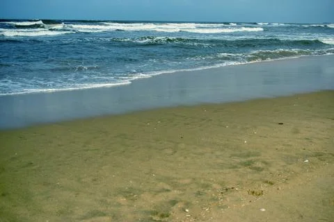 Ocean Waves Creating Foamy Patterns Along a Sandy Beach Shore Stock Photos