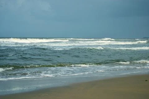 Ocean Waves Creating Foamy Patterns Along a Sandy Beach Shore Stock Photos