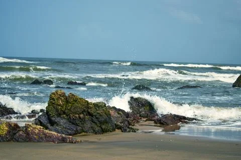 Ocean Waves Creating Foamy Patterns Along a Sandy Beach Shore Stock Photos