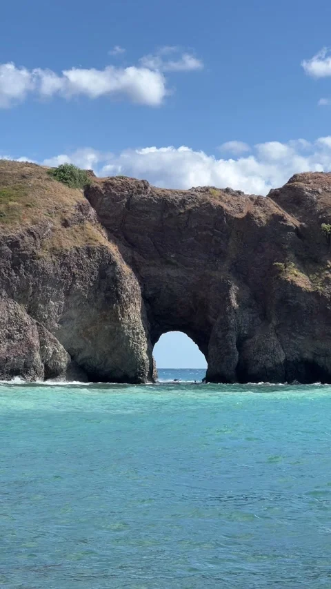 Ocean waves flowing through a natural rock arch on the coast Stock Footage 288027472