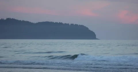 Ocean waves with a forested ridge at sunset 库存影片 251502703