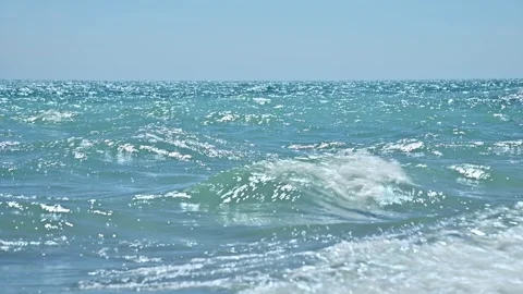 Ocean waves gently rolling onto sandy beach under clear blue sky Stock Footage 341475213