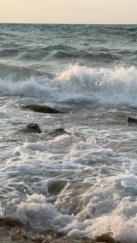 Ocean waves gently rolling onto the shore at sunset Stock Footage 304879369