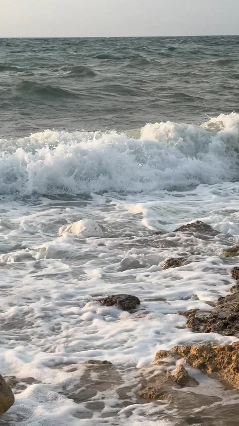 Ocean waves gently rolling onto the shore at sunset Stock Footage 304879372