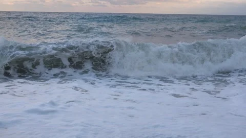 Ocean waves with heavy white foam run on pebble beach in stormy evening Stock Footage 254896917