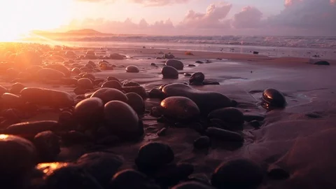 Ocean waves hit pebbles on the beach in golden sunset light in Famara Lanzarote Stock Footage 89144270
