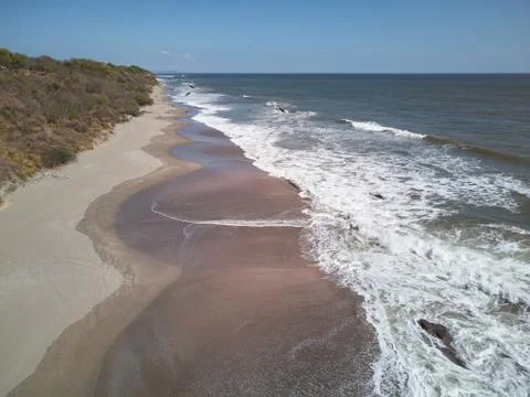 Ocean waves hit sandy beach Stock Photos