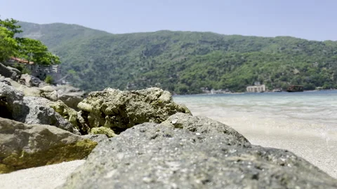 Ocean Waves Hitting Rocks Along Shoreline Near Small Island Village Vídeo Stock 241566253