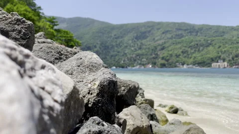 Ocean Waves Hitting Rocks Along Shoreline Near Small Island Village Video stock 241566373