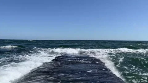 Ocean waves hitting stone breakwater creating white splash Stock Footage 329319794