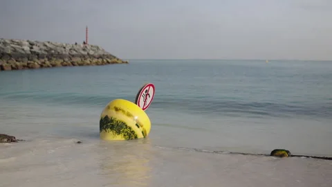 Ocean waves move floating buoy with a rope lies on the sand after low tide. The Stock Footage 245107701