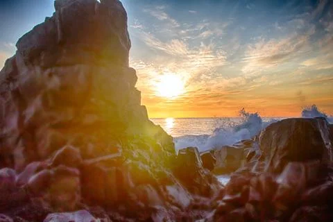 Ocean waves to rocks in sunset Stock Photos