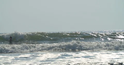 Ocean waves roll in as a group floats beyond Stock Footage 108628830