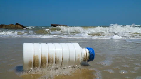 Ocean waves roll a plastic bottle on ocean shore. Pollution Stock Footage 106017445