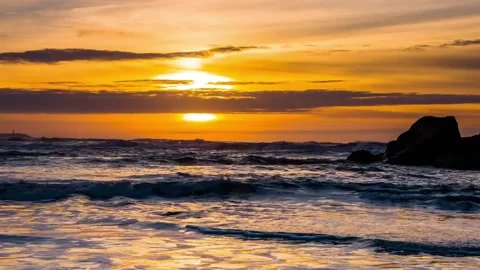 Ocean waves rolling onto beach during golden hour sunset wide shot Stock Footage 342138994