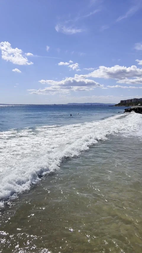 Ocean Waves Rolling onto a Sandy Beach Under a Clear Blue Sky Stock Footage 303412554