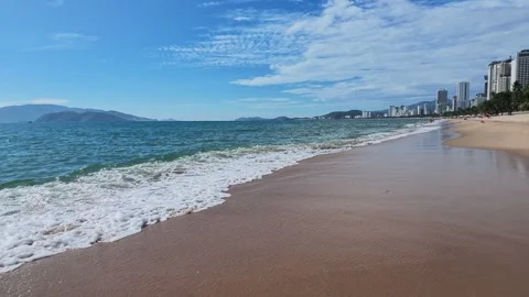 Ocean Waves Rolling on Sandy Beach with City Skyline Background Stock-Footage 345013018