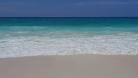 Ocean waves rolling onto sandy beach, tropical seascape, clear blue sky Видео 347572131