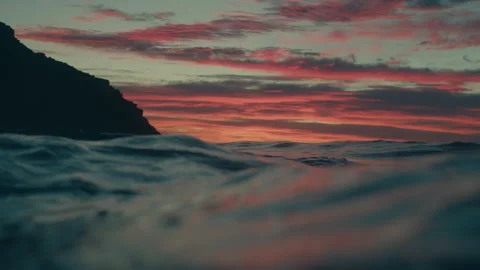 Ocean waves rolling at sunset red orange clouds coastal headland silhouette Stock Footage 333445740