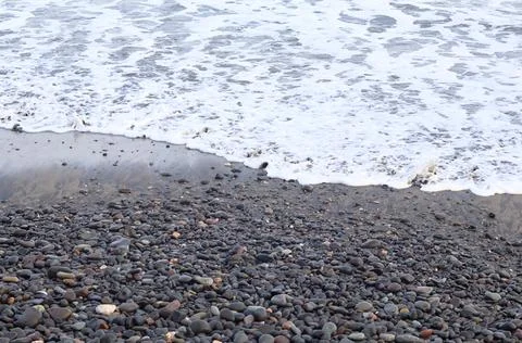 Ocean waves rolling toward a wet pebble beach Stock Photos