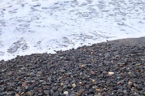 Ocean waves rolling toward a wet pebble beach Stock Photos