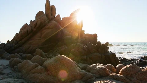 Ocean waves rushing over jagged rocks by the beach. Sun reveal. truck right Stock Footage 107009186