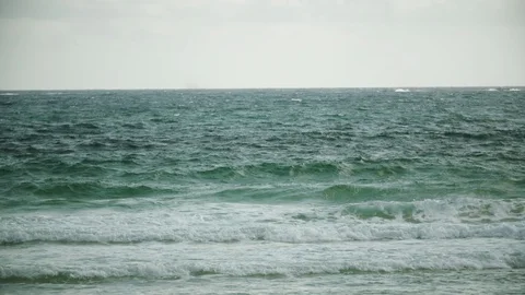 Ocean waves rushing towards beach on a sunny day Stock Footage 117741883