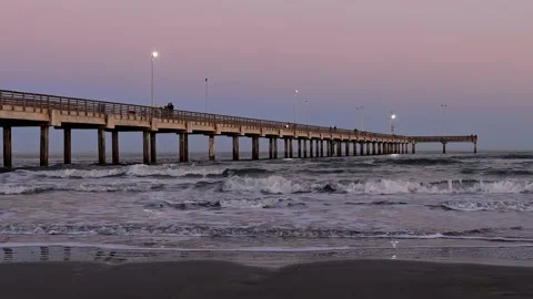 Ocean waves, sand beach by a pier in evening light. Two clips with zoom. Stock Footage 236965420