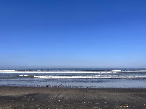 Ocean Waves on Sandy Beach Under Clear Blue Sky Stock Photos