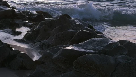 Ocean waves in slow motion, splashing over rocks on the shore at dusk. Vídeos de archivo 115999516