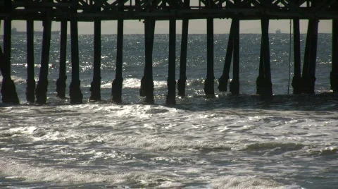 Ocean waves splash against the pier's support columns (High Definition) Stock Footage 360059