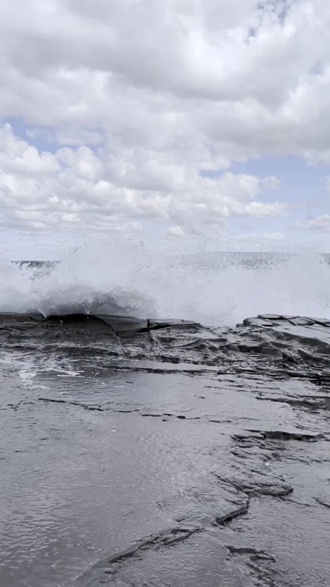 Ocean Waves Splash Over Coastal Rocks in Vertical Shot 스톡 동영상 345209830