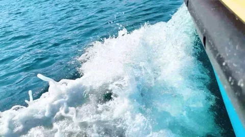 Ocean waves splashing beside moving boat hull in turquoise sea Stock Footage 340533308