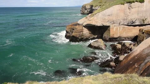 Ocean waves surging into the sandstone cliffs by Tunnel Beach, New Zealand. Stock Footage 135305493
